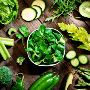 Bowl of spinach surrounded by other ingredients for the perfect green juice
