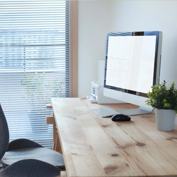 wood desk with a monitor and a printer next to a window