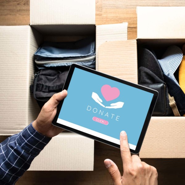 person confirming a donation on their ipad above boxes of clothes they are donating