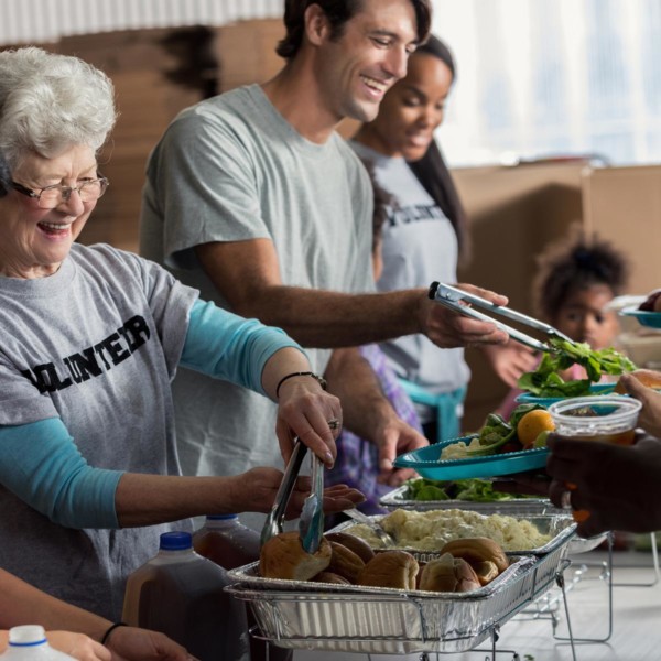 a group of people volunteering by giving out food to people who need it