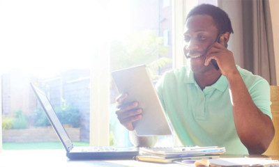 Man managing his finances on multiple devices including his phone, tablet and laptop