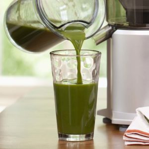 Image of someone pouring cold pressed green juice.