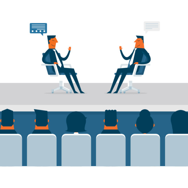 Image of people watching two people sitting in chairs having a conversation.