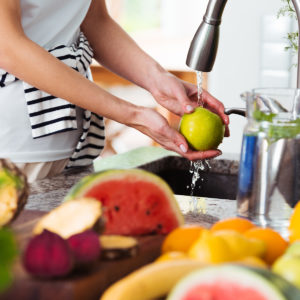 Woman washing green apple in sink before adding to her green juice