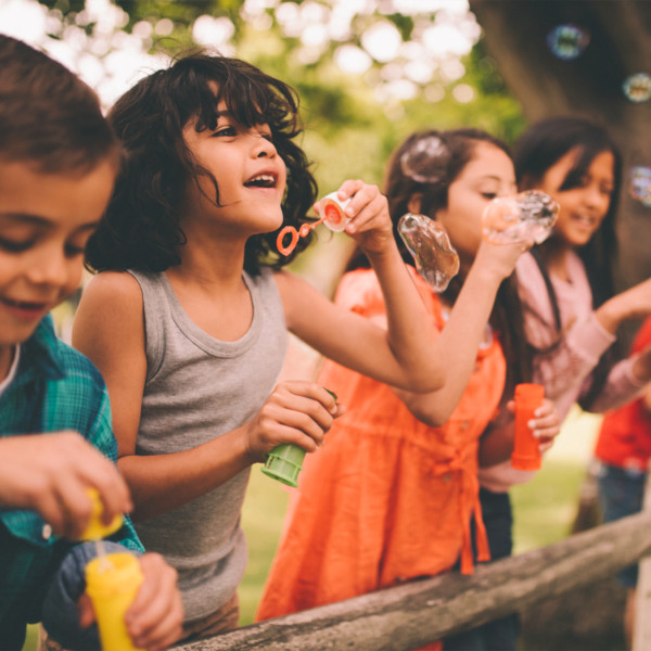 Image of kids blowing bubbles outside.