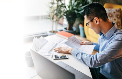 man reviewing papers with calculator to manage debt