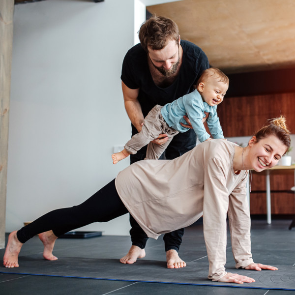 Mom doing yoga while dad plays with baby