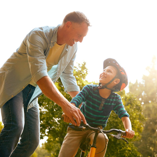 Image of a dad helping his son ride a bike